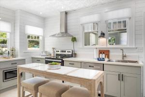 a kitchen with white cabinets and a table with stools at 2BR Bungalow Near AMI! King, W/D, Long-Stay Deals in Bradenton +18 photos