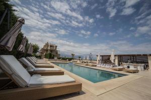 a swimming pool with lounge chairs and umbrellas at Niovi Boutique Apartments in Afitos