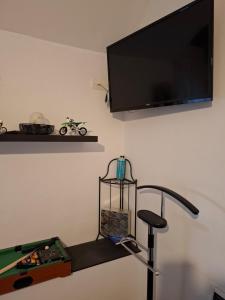 a flat screen tv hanging on a wall with a treadmill at Chambre avec SDB privative et parking MOTO ou VL in Romorantin