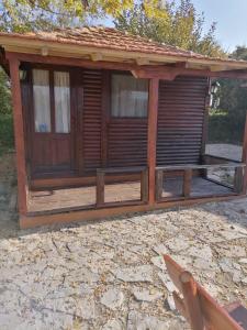 a wooden cabin with a porch on a stone patio at Brvnare Rodjak sa sela in Mionica