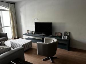 a living room with a flat screen tv and chairs at Apartamento Centro Serra Negra in Serra Negra