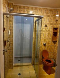 a bathroom with a toilet and a glass shower at Apartamento Centro Serra Negra in Serra Negra