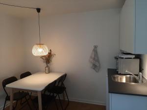 a kitchen with a table and a sink and a lamp at Mini-lejlighed med køkken - Deler bad og toilet med nabolejlighed 3 in Asperup +10 photos