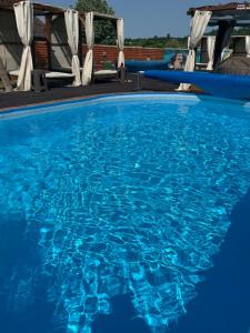 a swimming pool with blue water and white chairs at Brvnare Rodjak sa sela in Mionica