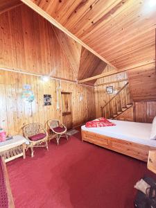 a bedroom with a bed and chairs in a wooden room at KOLAKHAM SILVERPINE RETREAT HOMESTAY Pure Veg KOLAKHAM,LAVA in Lava +2 photos