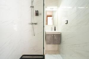a white bathroom with a shower and a sink at Résidence Dunkerque - Duplex in Casablanca +52 photos