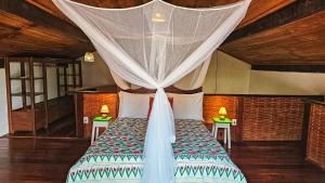 a bedroom with a bed with a mosquito net at Canoa Nativa Pousada Boipeba in Ilha de Boipeba