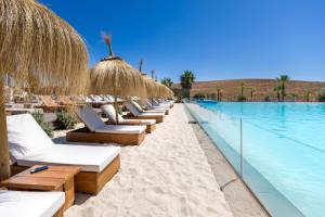 Una fila de tumbonas junto a una piscina. en Brand New Stylish Retreat in Alcazaba Lagoon - Estepona, en Estepona