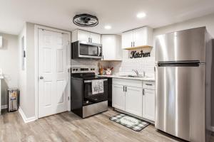 a kitchen with white cabinets and a stainless steel refrigerator at The Cozy Cottage in Waycross