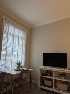 a living room with a flat screen tv and a table at Woodside Bungalow in Stevenston