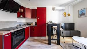 a kitchen with red cabinets and a table in it at Le Reflet - Vue Rivière et Caractère in Dijon +11 photos