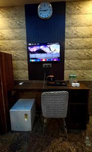 Bahādurgarhにあるhotel Metroview room&celebrationのデスク、テレビ、時計が備わる客室です。