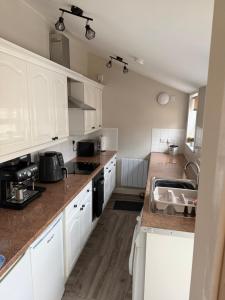 a kitchen with white cabinets and a sink at Woodside Bungalow in Stevenston