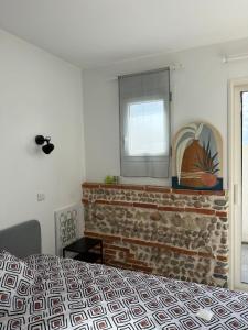 Saint-Orens-de-GamevilleにあるAppartement climatisé Saint Orens N8のベッドルーム(ベッド1台、レンガ造りの暖炉付)