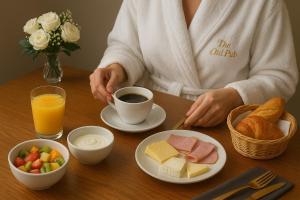 a woman sitting at a table with a cup of coffee and food at The Old Pub Unique Modern Extra Large Private Cellar with Sauna Gym King Size Bed Snacks Mini Bar and Continental Breakfast Fully Self Contained in Patney