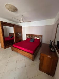a bedroom with a large red bed and a mirror at Résidence Cheikh in Ngaparou
