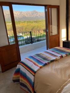 une chambre avec un lit et une porte coulissante en verre dans l'établissement Casa de Las Brujas Traslasierra, à Los Molles