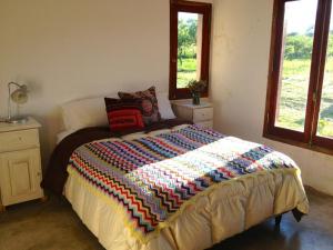une chambre avec un lit avec une courtepointe colorée dessus dans l'établissement Casa de Las Brujas Traslasierra, à Los Molles 36 autres photos