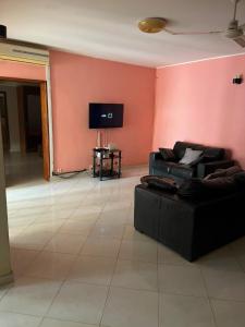 a living room with two couches and a flat screen tv at Résidence Cheikh in Ngaparou
