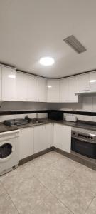 une grande cuisine avec des placards blancs et une cuisinière dans l'établissement Casablanca - Playa Romana1, à Alcossebre