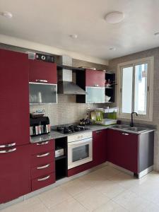 een keuken met rode kasten en een kookplaat oven bij Sweet Home Agadir Appartement moderne avec piscine et commerces à pied in Agadir