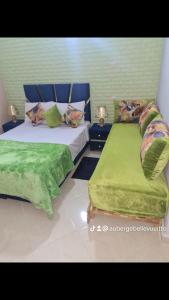 a bedroom with two beds with green sheets and pillows at Hôtel mandar itto in Azrou