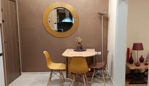 a dining room table with yellow chairs and a mirror at Διαμέρισμα στο κέντρο της Θήβας in Thiva +3 photos