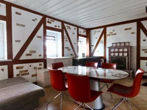 Un comedor con una mesa de cristal y sillas rojas. en Kauno Marių Vilos, en Samylai