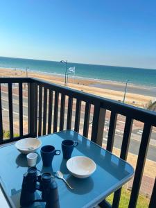 a table on a balcony with a view of the beach at Cote et Mer Superbe appartement Front de Mer WIFI & PARKING in Villers-sur-Mer