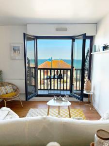 a living room with a couch and a view of the ocean at Cote et Mer Superbe appartement Front de Mer WIFI & PARKING in Villers-sur-Mer