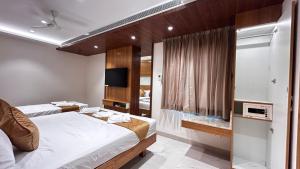 a hotel room with two beds and a television at The Paradise Platinum in Kanchipuram