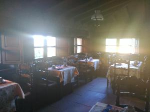 una sala da pranzo con tavoli, sedie e finestre di Posada Rural Valoria a Valoria