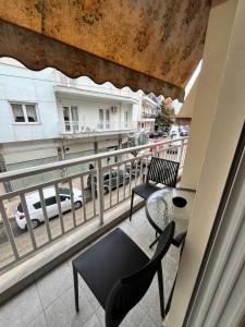 balcón con sillas, mesa y vistas a la calle en KN Luxury Apartment, en Alexandroupoli