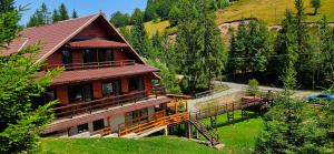 a large wooden house with a bridge in front of it at Cabana Cota 1000 Arieseni in Arieşeni