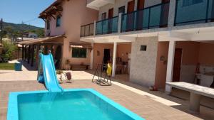 a blue swimming pool in front of a house at Casa para temporada, São Pedro da Aldeia - RJ in São Pedro da Aldeia