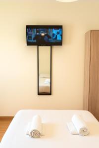 a tv on a wall above a bed with towels at Sol y Olivos Apartamentos de 1 o 2 dormitorios en el centro de Jaén in Jaén +9 photos