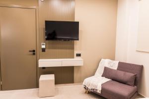 a living room with a couch and a tv on a wall at Infinity Palm Villa in Stavros