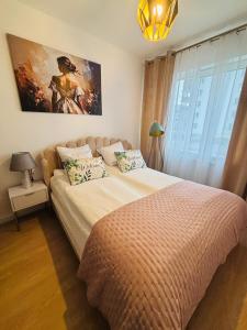 a bedroom with a bed and a painting on the wall at Lotus Apartments Impero oddzielna kuchnia 2 pokoje garaż in Ostrołęka