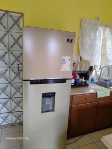 a white refrigerator in a kitchen next to a counter at The Luxe Spot in Spanish Town +13 photos