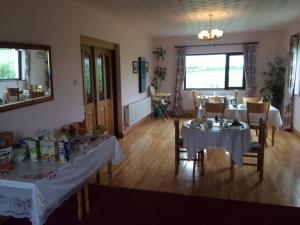 a dining room with two tables and a mirror at Greenfields Farmhouse in Ballylongford