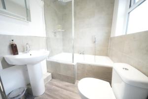 een badkamer met een wastafel, een toilet en een ligbad bij Private Rooms-Private Bathrooms-Near Airport- CABIN CREW paradise in Harmondsworth