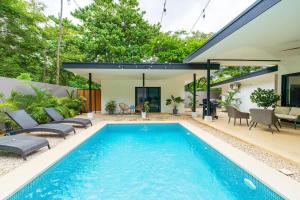 a swimming pool with a patio and a house at Serenity Surf Villa in Playa Grande