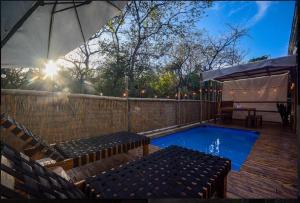 a swimming pool with benches and an umbrella at Casita VNV in Nosara
