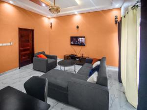 a living room with a couch and chairs and a tv at Fleur d'hibiscus in Cotonou