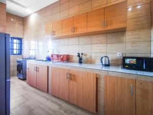 a kitchen with wooden cabinets and a microwave at Fleur d'hibiscus in Cotonou