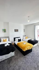 deux lits dans une chambre aux murs blancs dans l'établissement Jarrow Haven Contractor Family Stay with FREE Parking Sleeps 8, à Jarrow