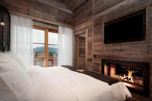 a bedroom with a fireplace and a bed and a tv at Hostellerie du Pas de l'Ours "Relais et Châteaux" in Crans-Montana +72 photos