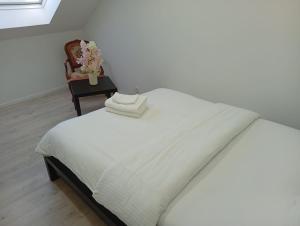 un lit blanc dans une chambre avec une chaise dans l'établissement studio supérieur, à Marcinelle