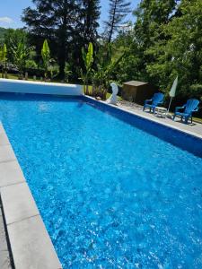 a large blue swimming pool with two blue chairs at Domaine mon doux rêve in Terrasson-Lavilledieu