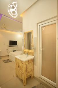 a bathroom with a sink and a mirror and a bed at White Lotus Homestay in Dibrugarh